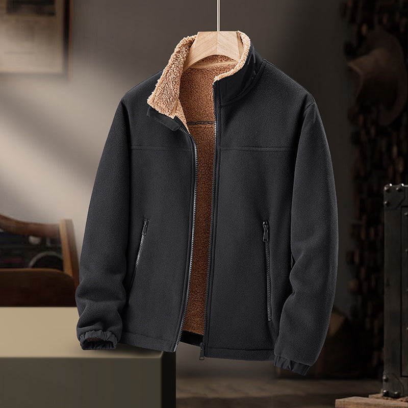 Giacca in pile nero con interno in pelliccia sintetica marrone, zip frontale, tasche laterali, appesa in un ambiente rustico. Abbigliamento invernale caldo.