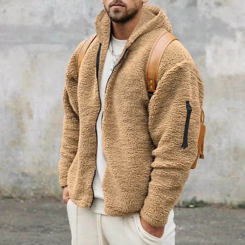 Uomo con giacca in pile marrone, zaino in pelle, sfondo grigio. Moda autunnale, abbigliamento casual, stile urbano.