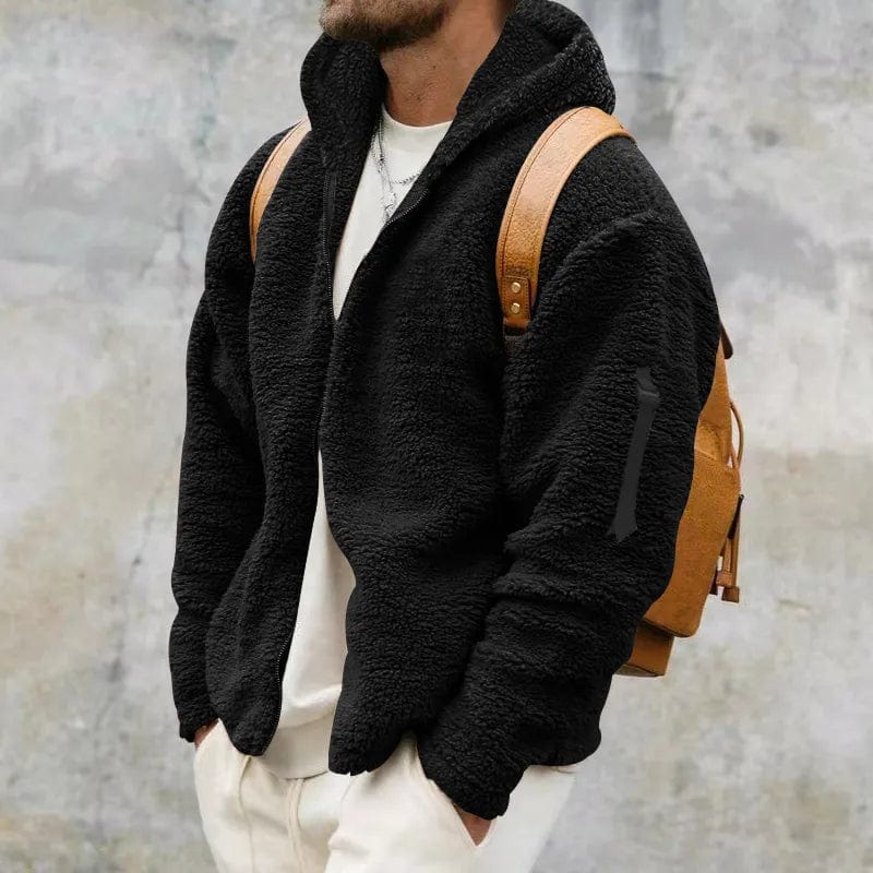 Giacca in pile nero uomo, stile casual, con zaino marrone. Moda autunnale, abbigliamento caldo e confortevole. Sfondo grigio urbano.